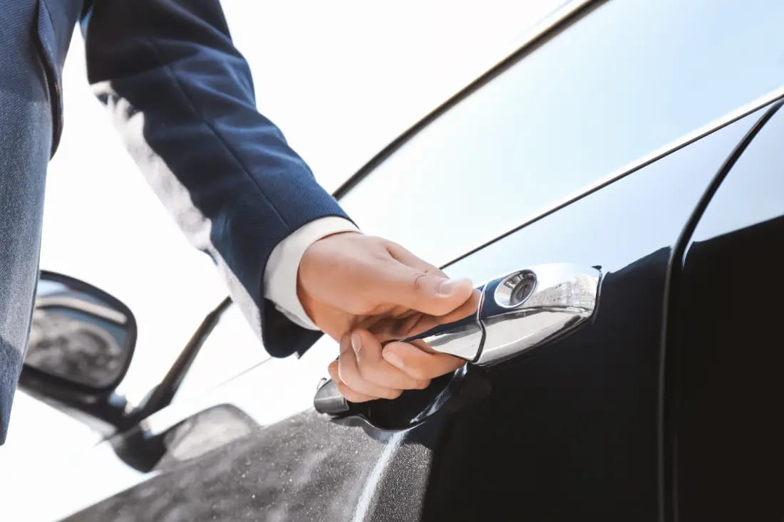 Chauffeur ouvrant la portière d'une voiture noire, gros plan. 