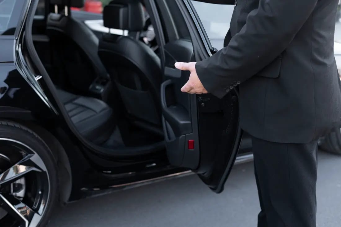Chauffeur tenant la porte d'une personne descendant d'une voiture noire